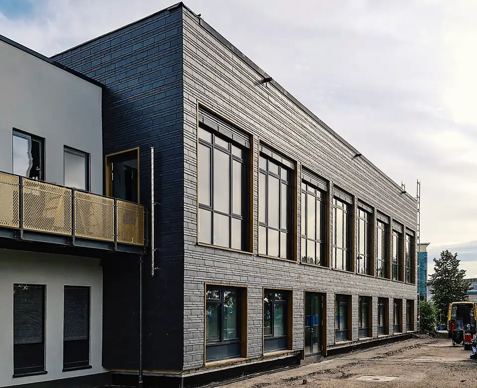 Modern two-story building with large windows and a balcony under a cloudy sky.